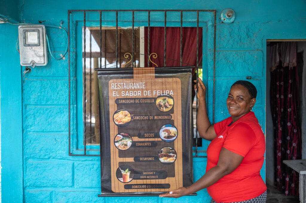 Felipa muestra el cartel de su restaurante El Sabor de Felipa en la fachada de su casa.