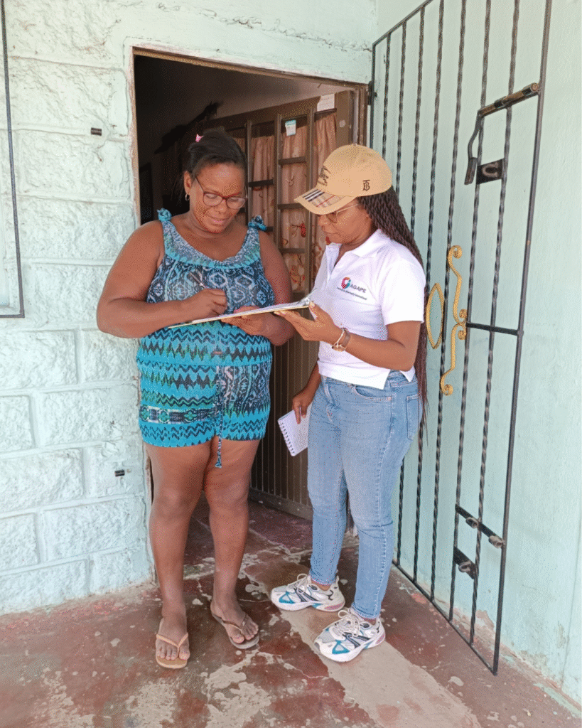 Supervisora del programa realiza visita domiciliaria y dialoga con participante en la puerta de su casa.