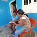 Mujer llena un formulario guiada por una supervisora del programa en un espacio comunitario.