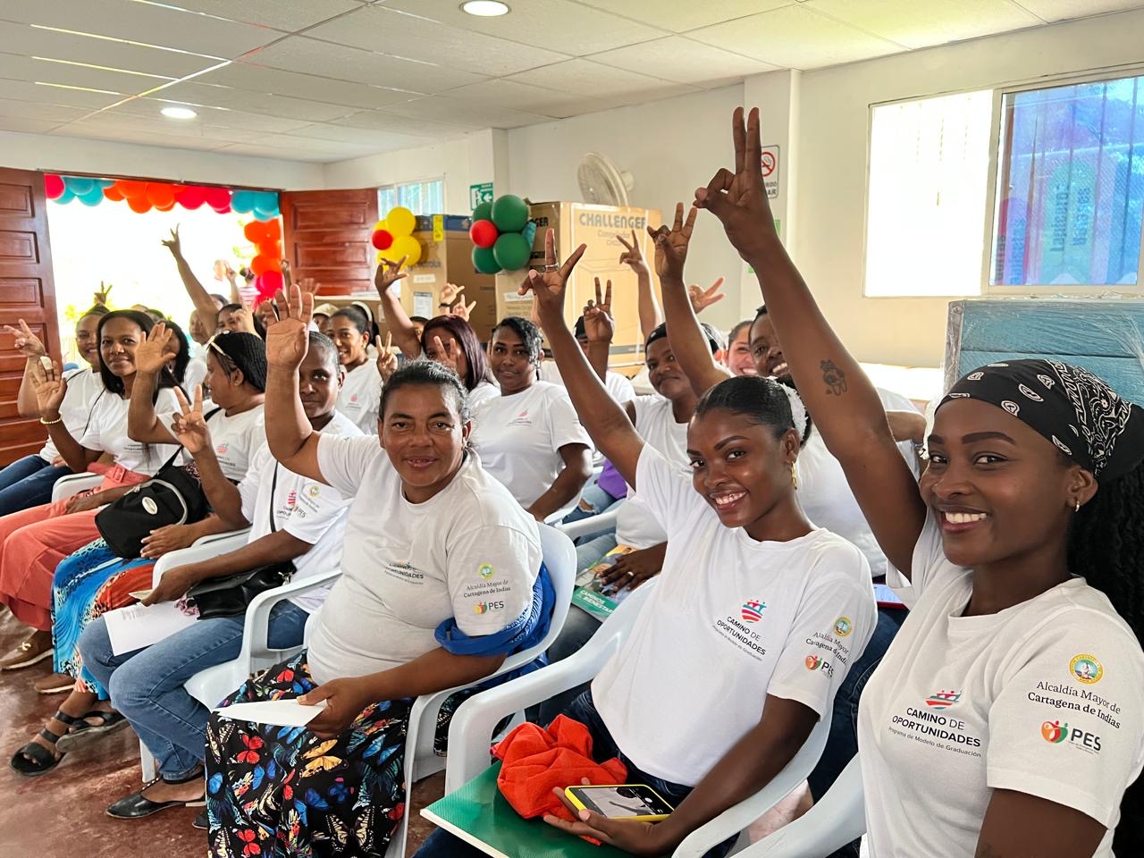 Familias participantes levantan la mano durante la entrega de capital semilla en Cartagena.